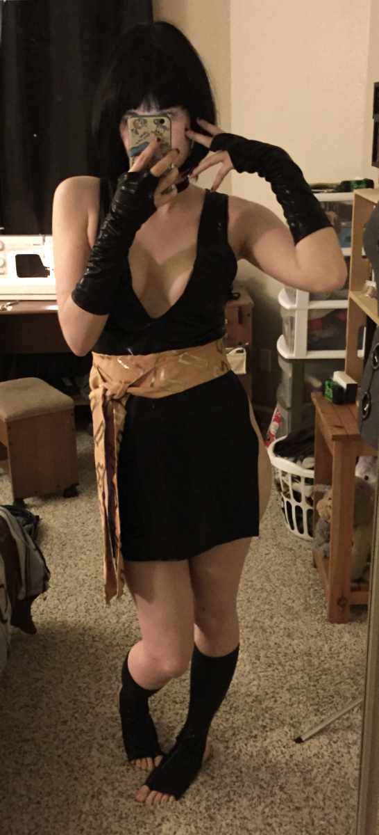 lynai in front of a mirror taking a selfie as yura. she's wearing a finished black dress, gloves wig and short calf leggings